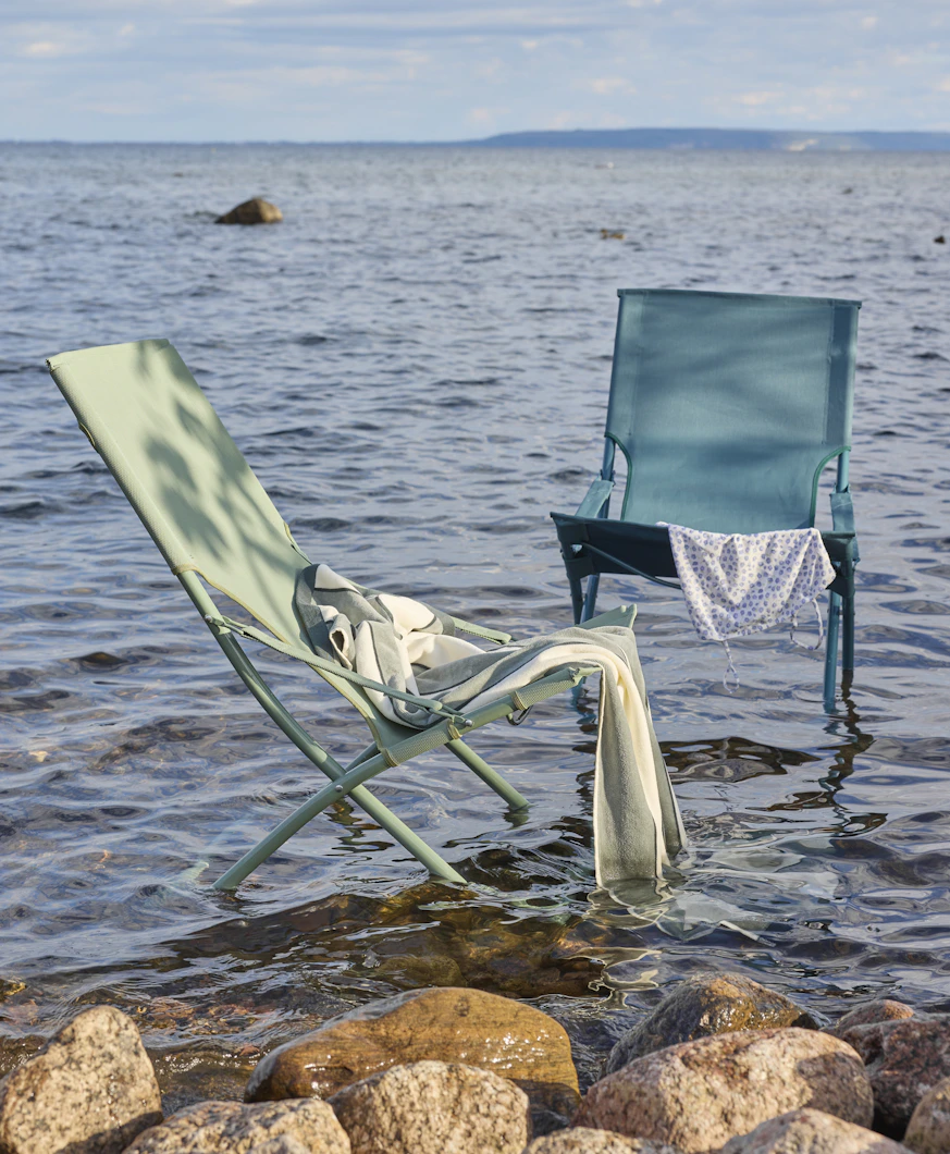 I grunt vatten står en grön och en turkos fällbar solstol