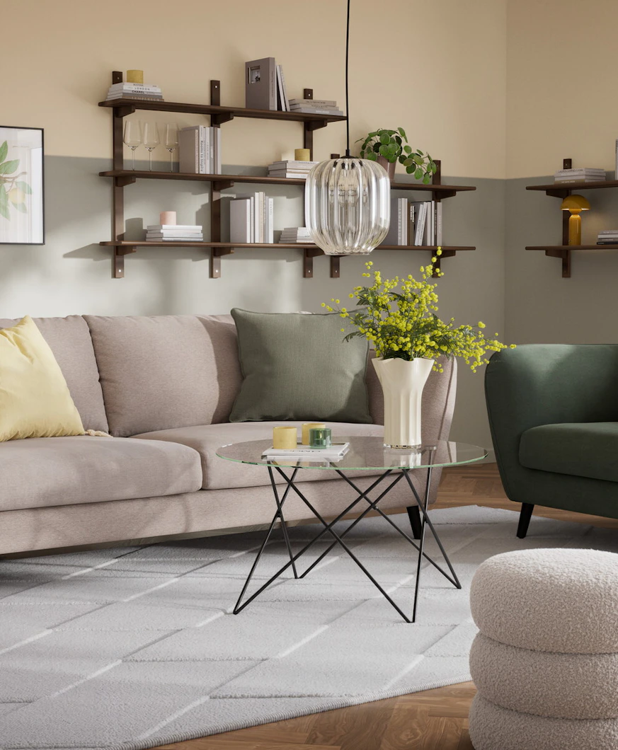 En beige soffa med färgglada kuddar och en grön fåtölj i samma stil står i ett vardagsrum med väggar i grönt och gult.