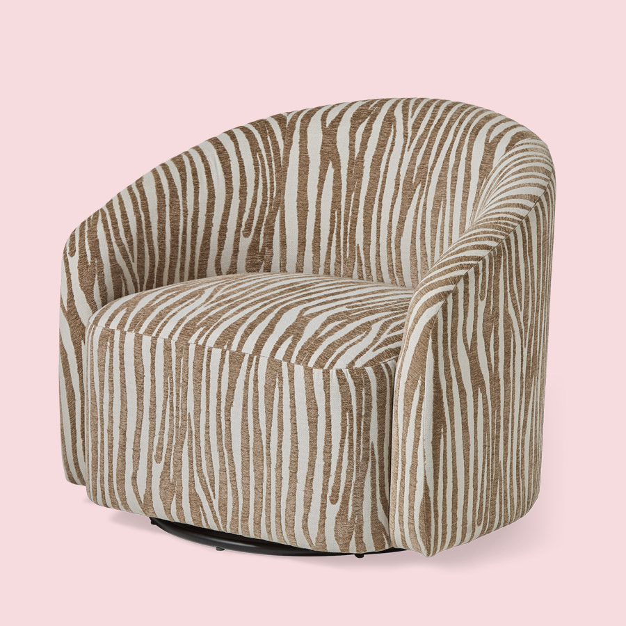 Fåtölj i beige zebramönster med runda former och snurrfot mot en ljusrosa bakgrund.