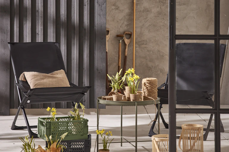 Två svarta solstolar står utomhus bredvid ett runt svart brickbord