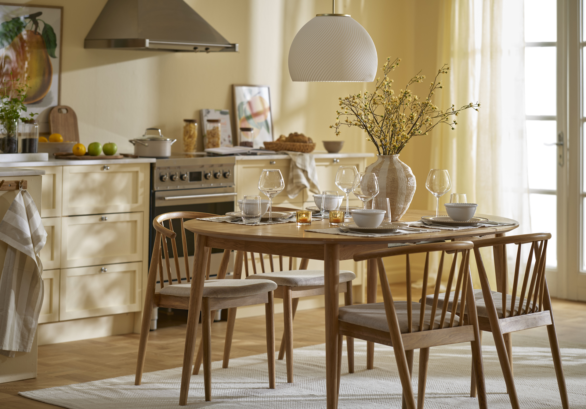 Ett matbord i ek med fyra stolar står i ett gult kök.