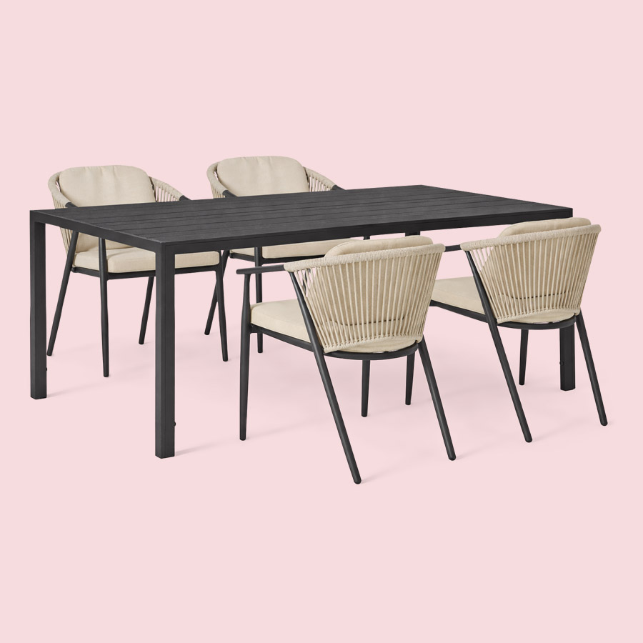 Utebord i svart konstträ och fyra karmstolar med dekorativ repflätning mot en rosa bakgrund.