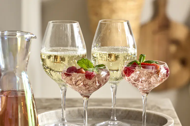 Två vinglas och två champagneglas står på en marmorbricka.