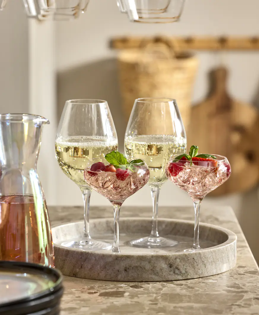 Två vinglas och två champagneglas står på en marmorbricka.