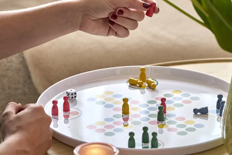 En person spelar Fia med knuff på ett soffbord i ljust trä.