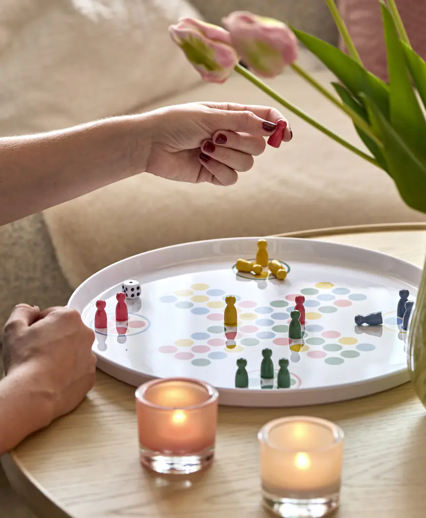 En person spelar Fia med knuff på ett soffbord i ljust trä.