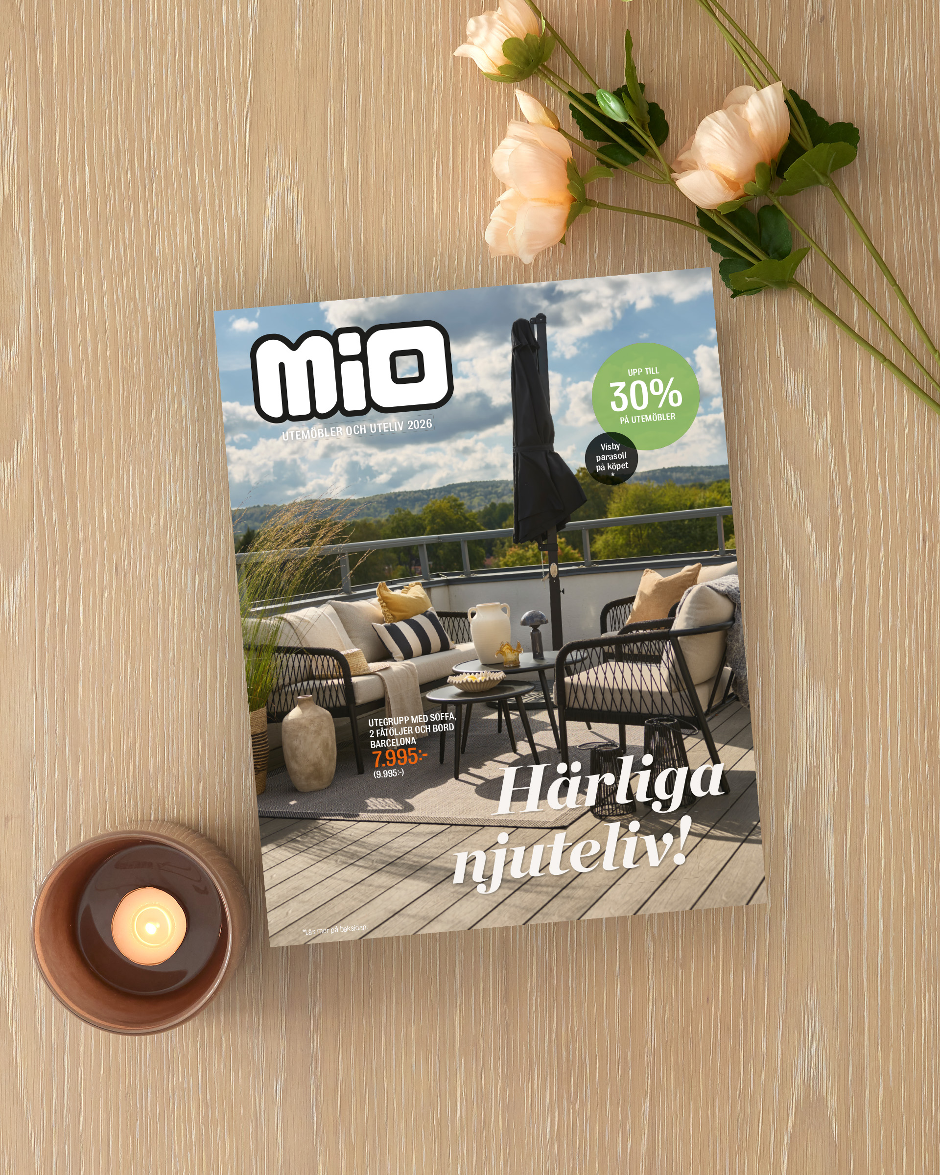 På ett ljust träbord ligger Mios utelivsbilaga intill ett ljus och en blomma.