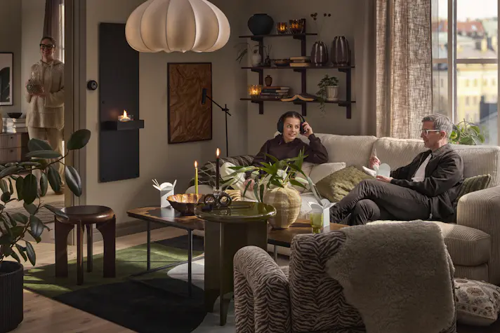 I en beige soffa sitter en man och äter och en tjej och lyssnar på musik i hörlurar.