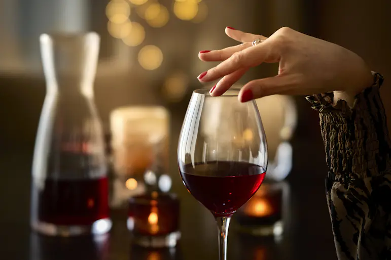 En kvinnlig hand håller på ett Orrefors-glas.