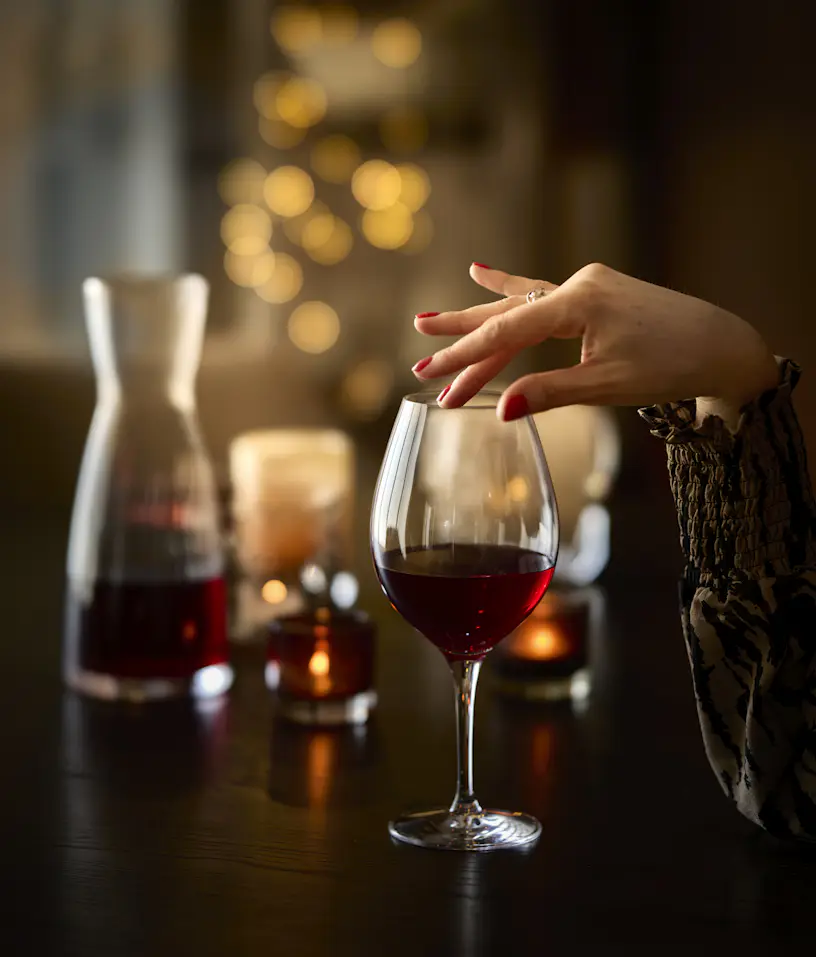 En kvinnlig hand håller på ett Orrefors-glas.