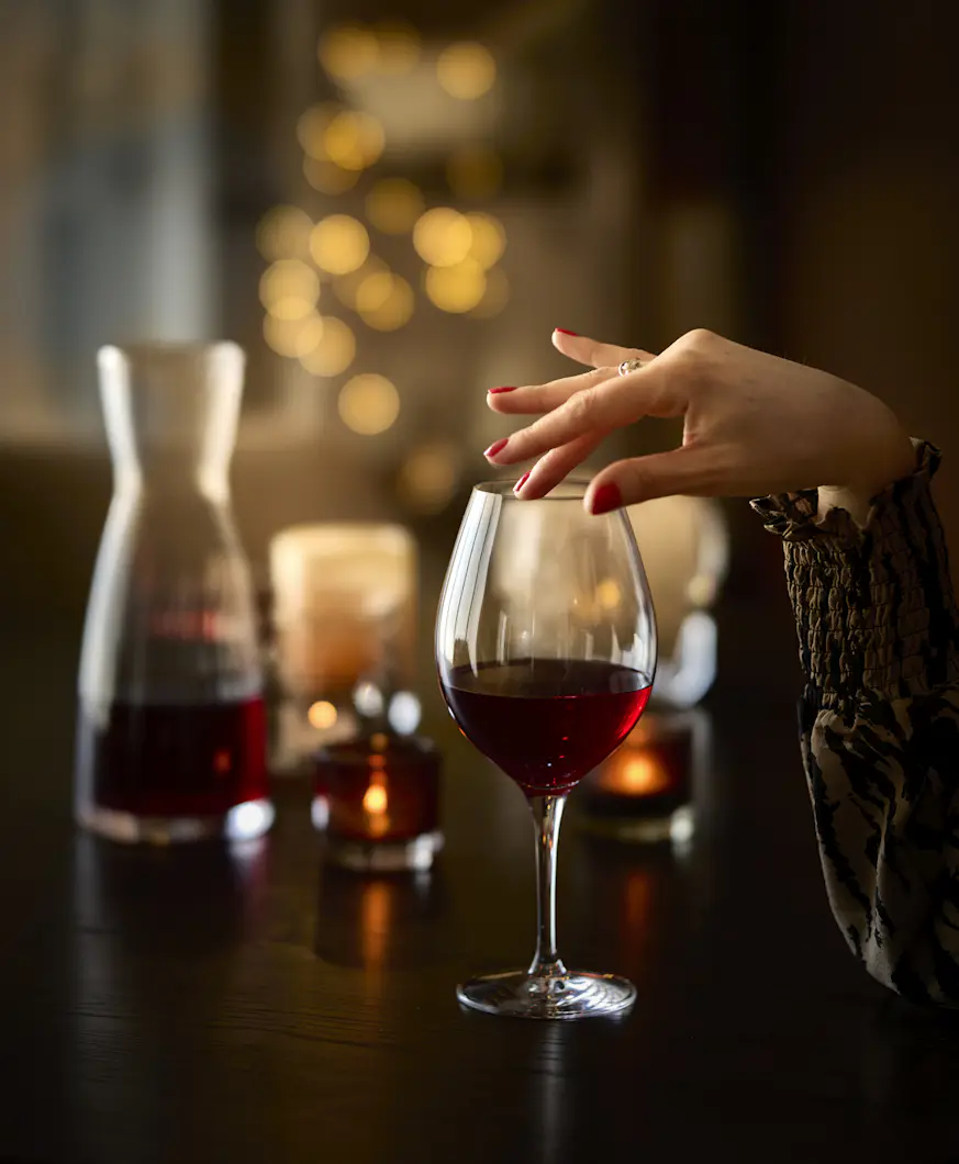 En kvinnlig hand håller på ett Orrefors-glas.