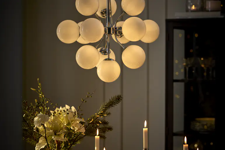Matplatsmiljö med närbild på en kromad taklampa som består av flera vita, bollformade ljuskällor.
