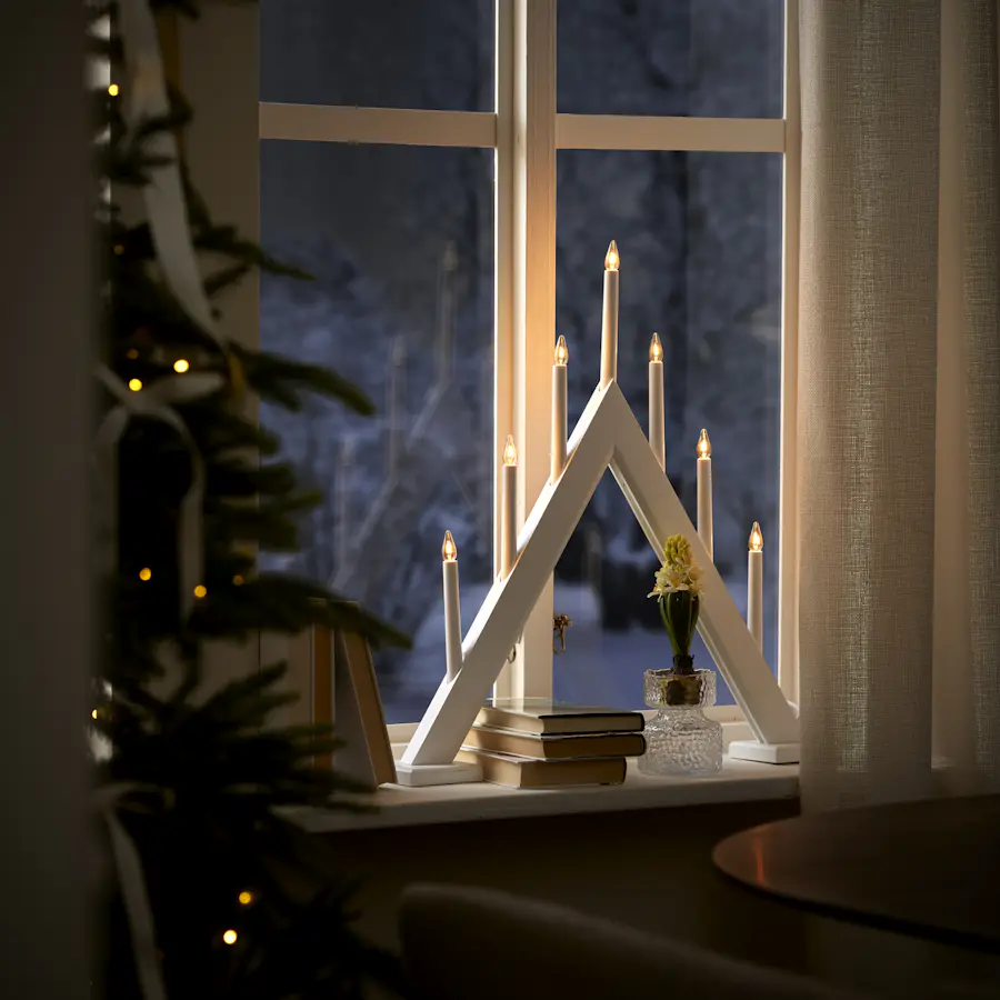 En vit adventsljusstake står i ett fönster